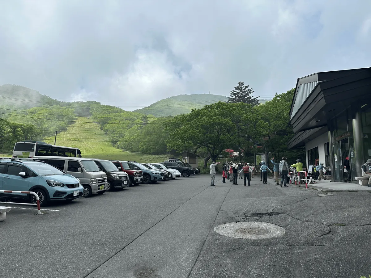 A building on the edge of the carpark, with lots hikers around.