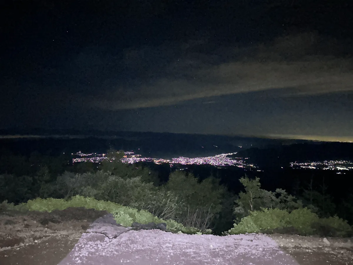 The path is partially illuminated by my headlamp, but can see out onto the city lights below