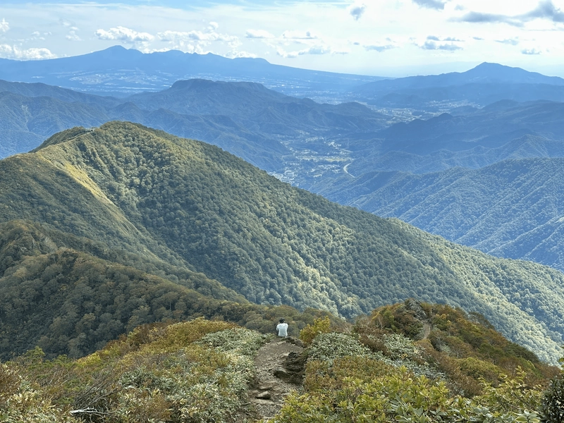 A person sitting down, overlooking the valley below.