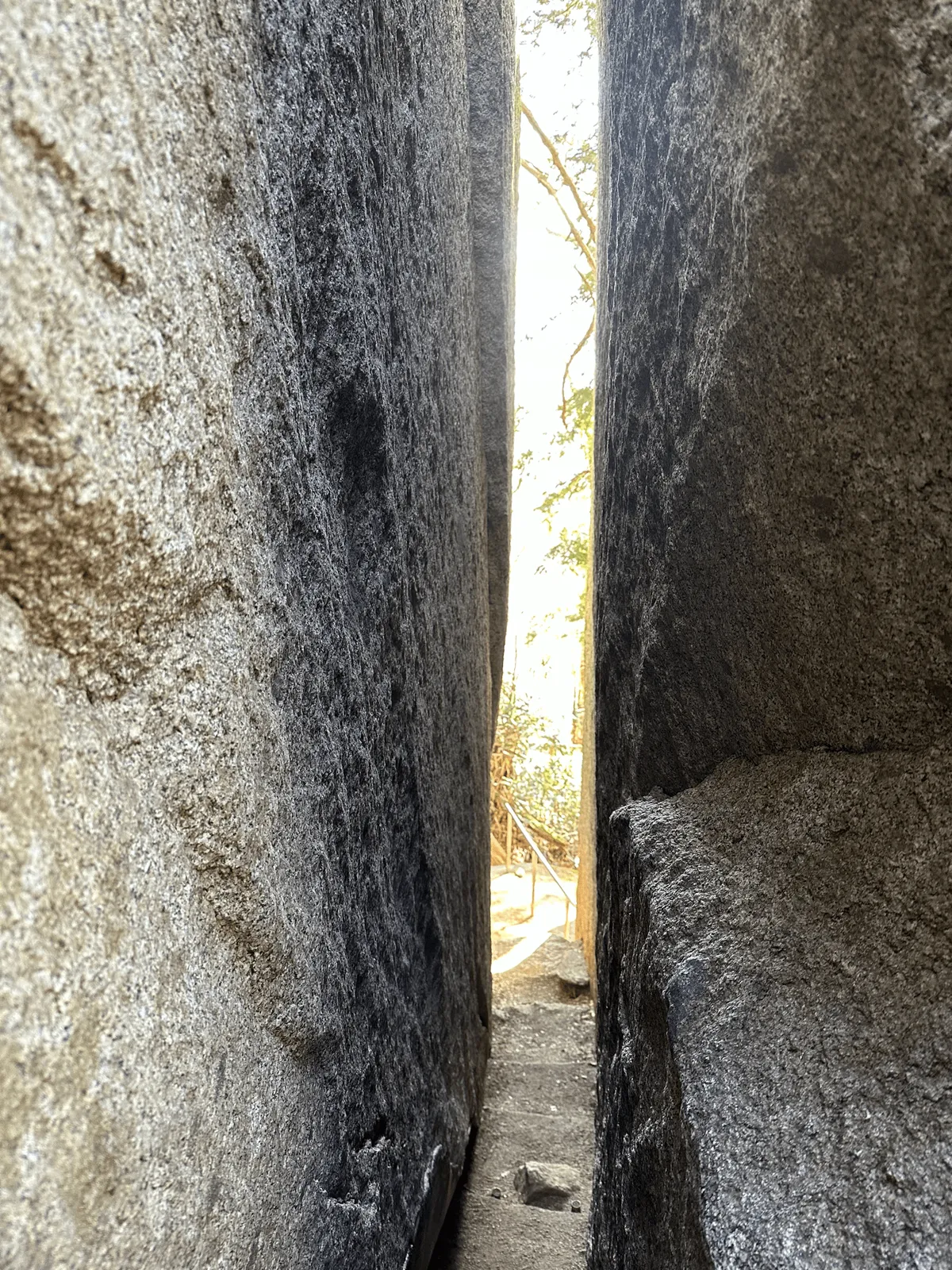 The rock is multiple metres high, but there's a crack in it thats wide enough for a person to squeeze through.