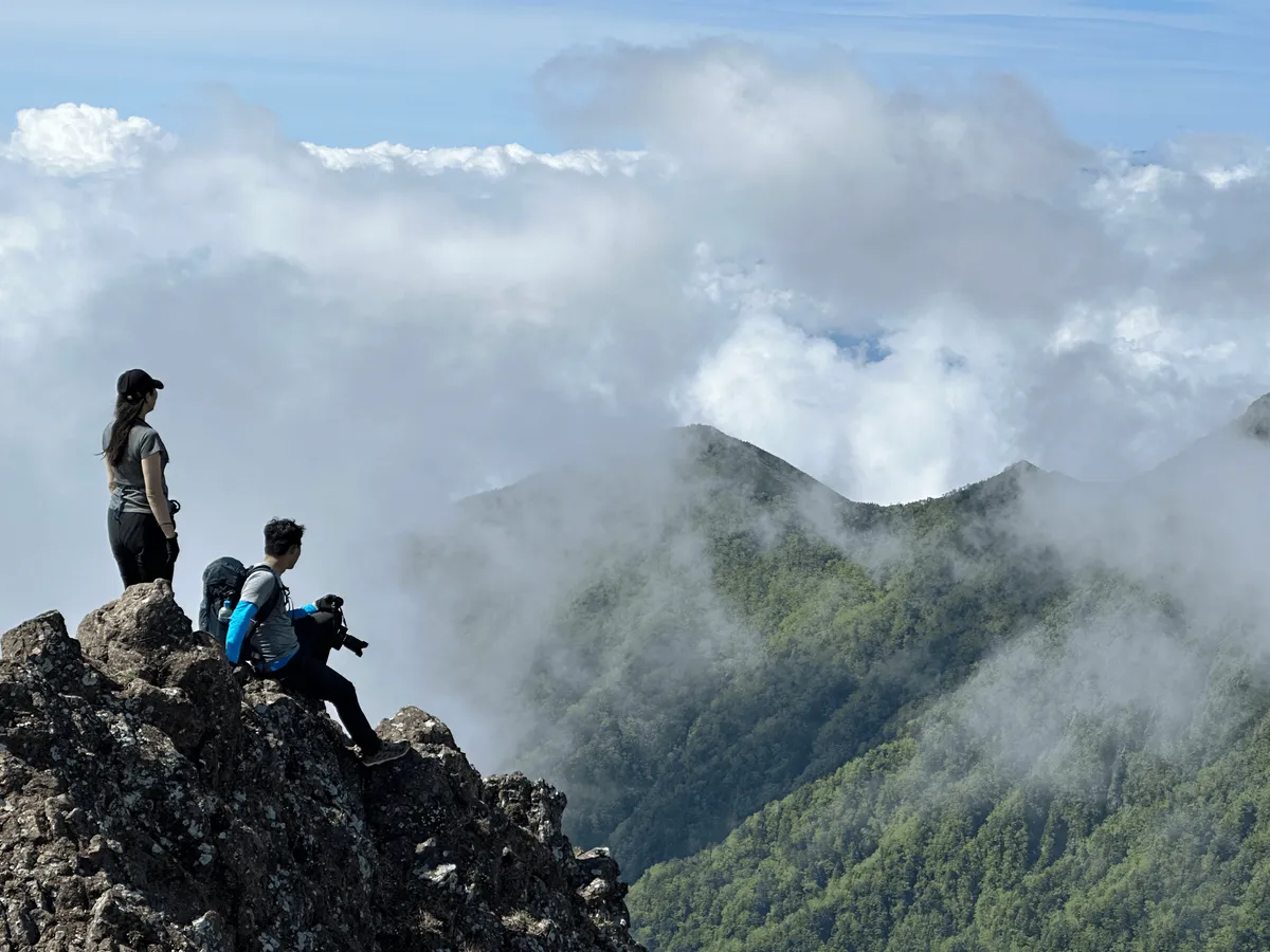 Two friends perched on the rock, overlooking the green below.