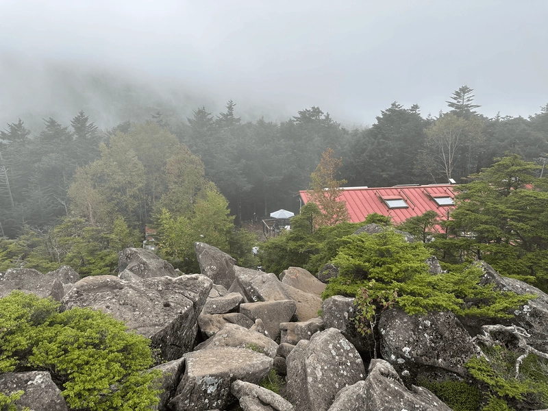 Between the sea of rocks, the red roof of the Takamishi mountain cabin pokes out