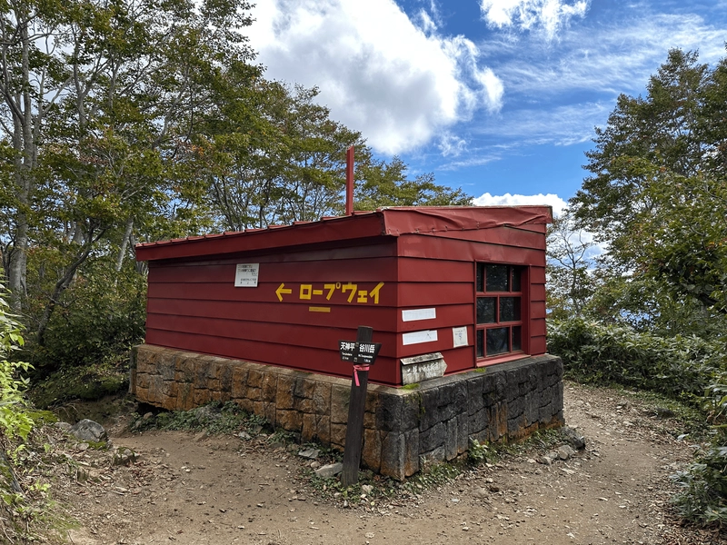 The refuge hut, which is a small red building with yellow letters.