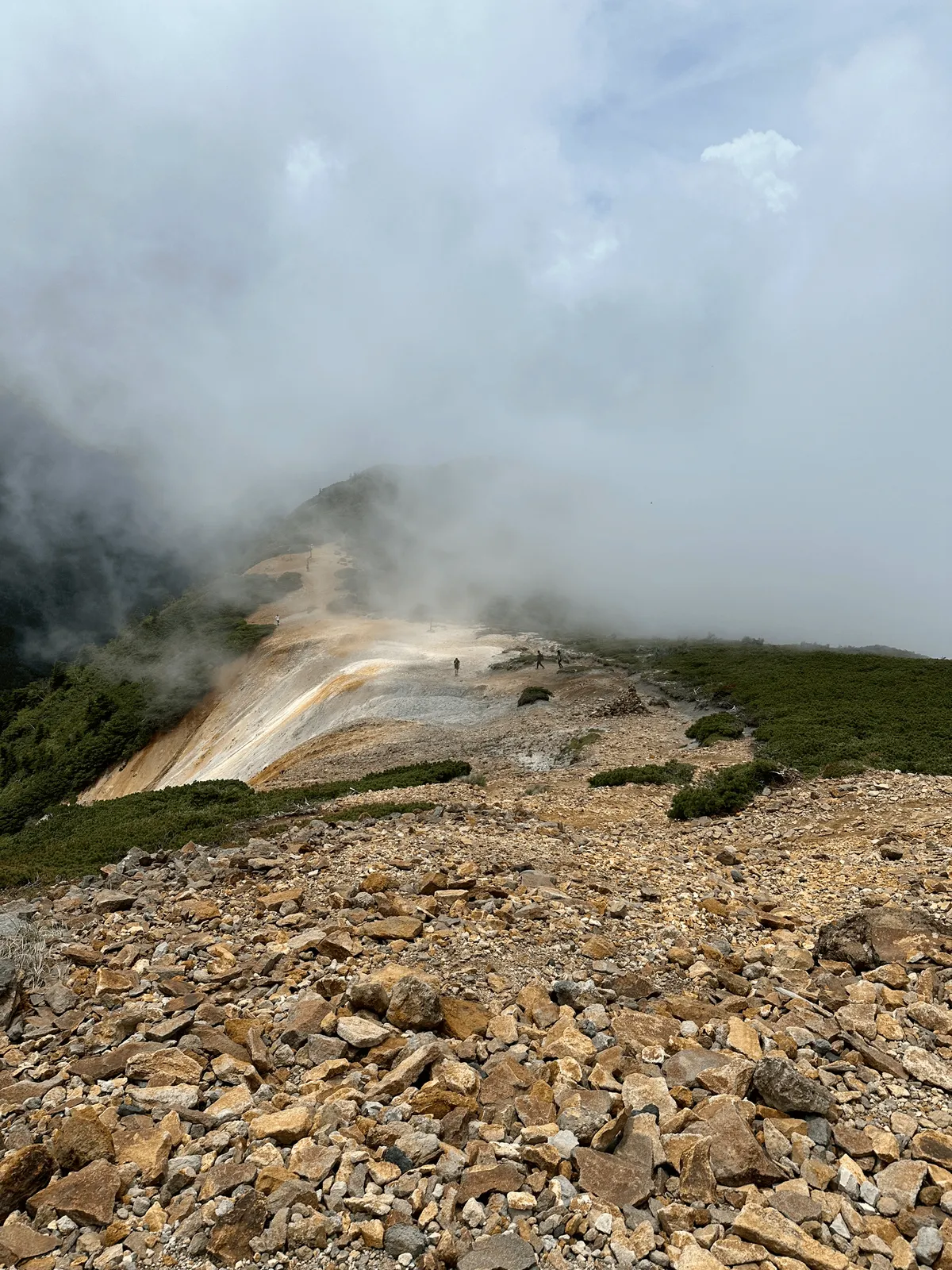 The path leads down a yellow ridgeline, coloured by a lot of flat rocks.