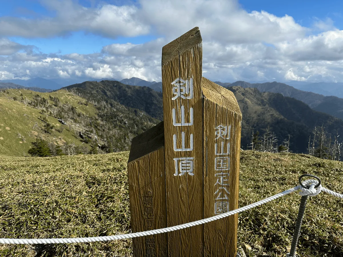 The wooden peak marker of Mt Tsurugi, the bottom bit obscured by a rope fence.