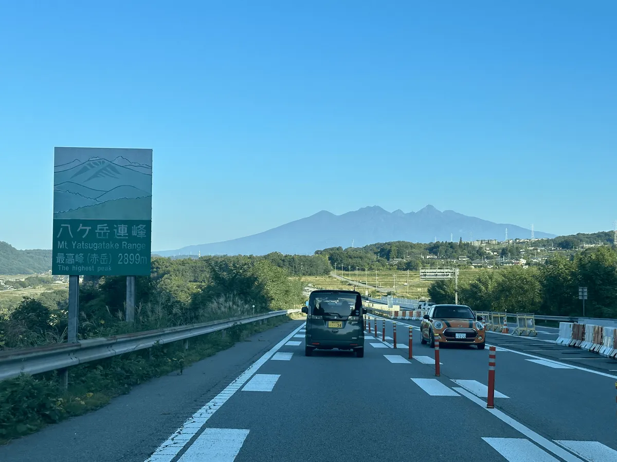 A photo taken from a highway road. The eight peaks of Yatsugatake stick out like teeth.