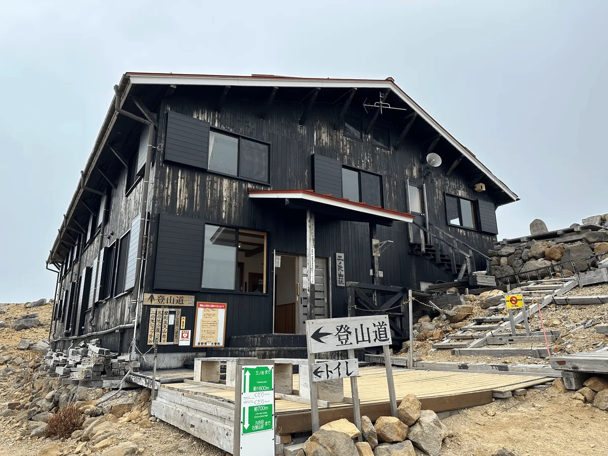 The hut is a large two-story building, wooden, painted mostly in black.