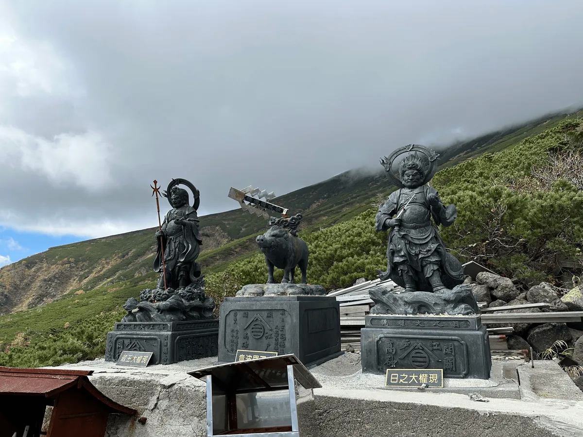 Two statues of deities and one of a pig in the middle.