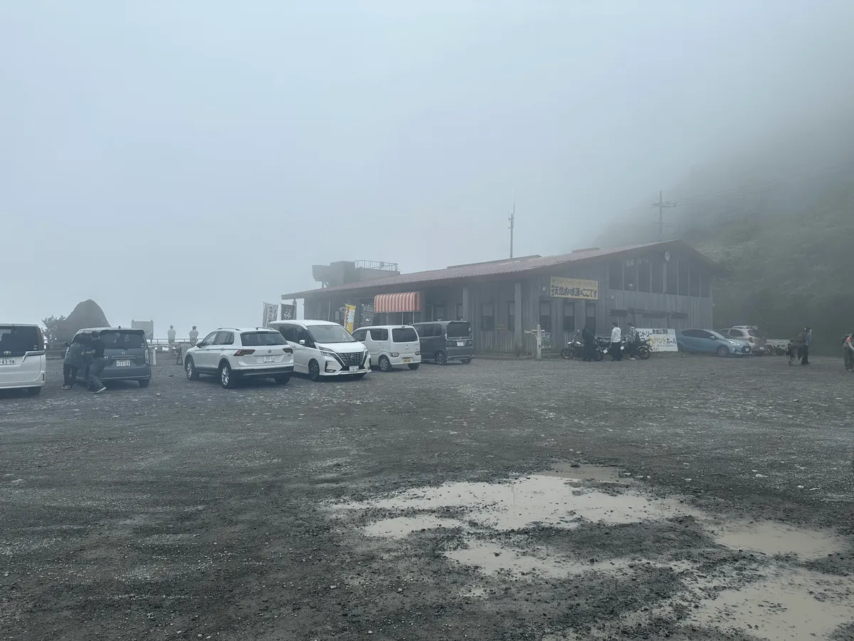 A non-descript building, with a couple of cars parked outside.