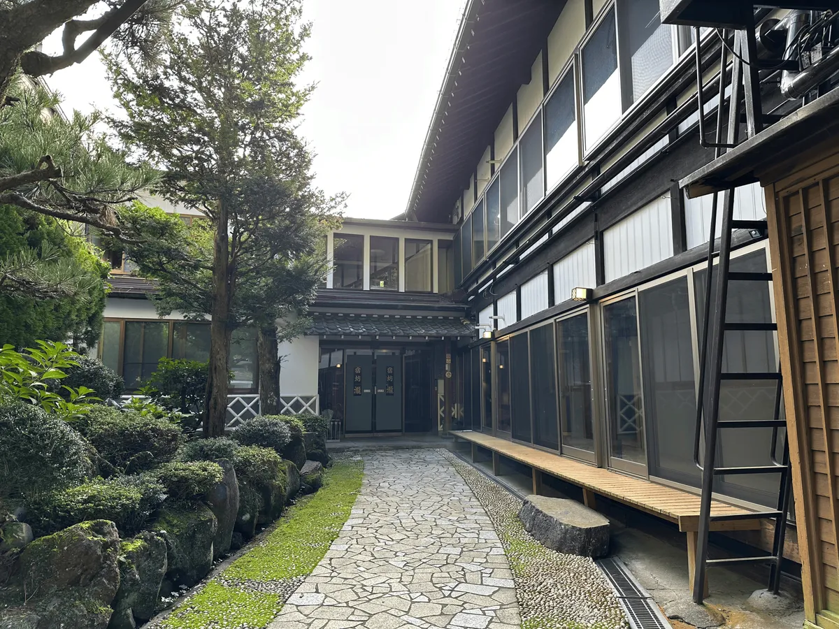 Entrance to the Taki Ryokan, a traditional Japanese building with a mossy garden.