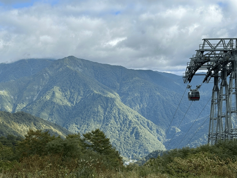 A ropeway car, with a green mountain range in the background.