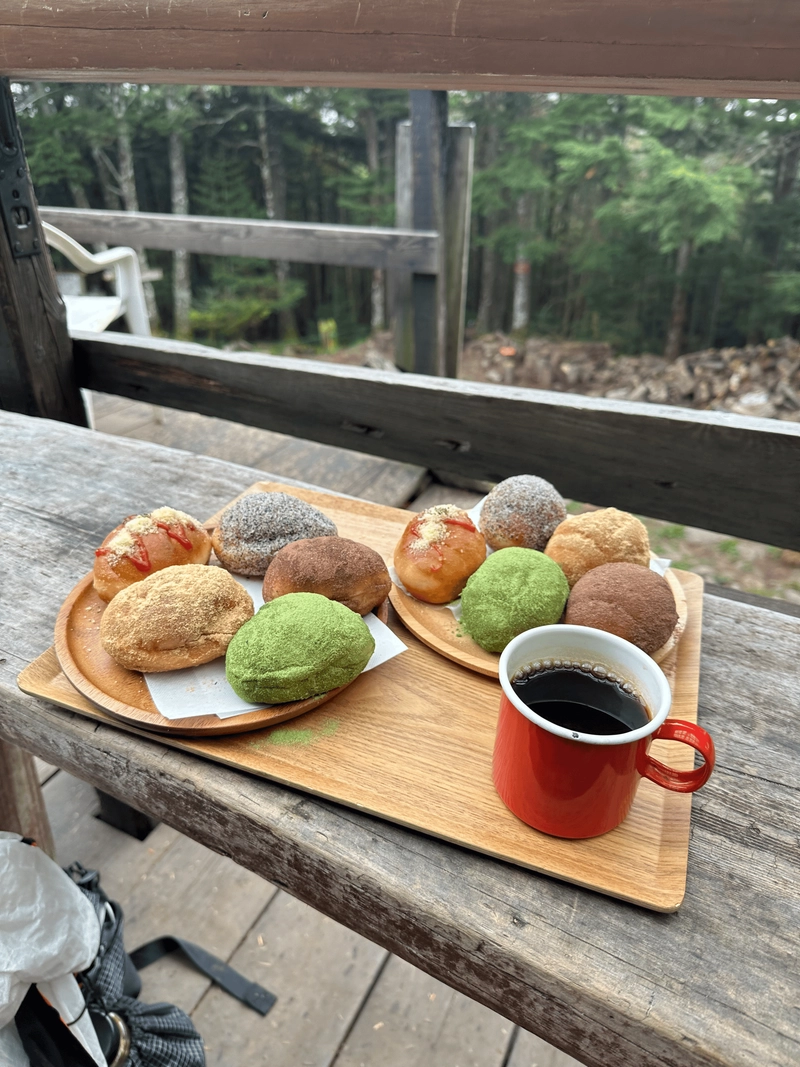 Two plates of five deep-fried bread rolls, all different colours, plus a coffee