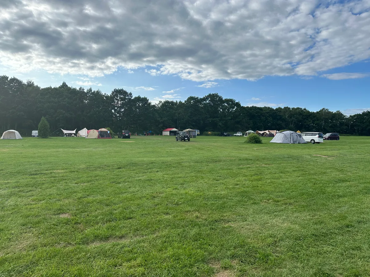 A large open field with a couple of tents.