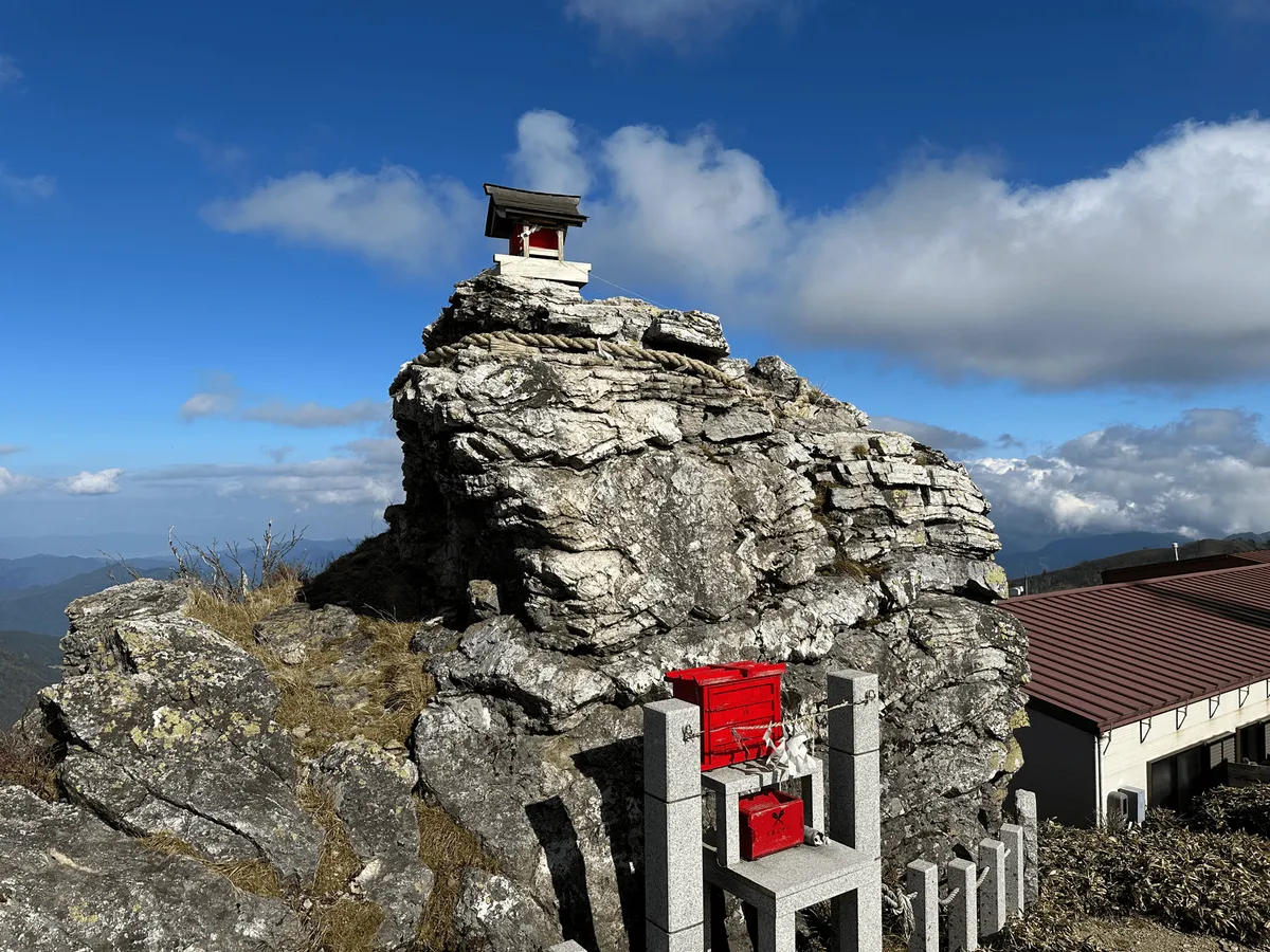 A large rock with a tiny little shrine perched atop it.